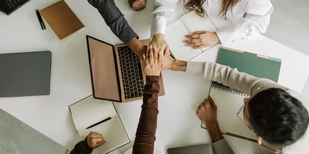 Team members stacking hands over a desk